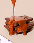 Caramel being poured over a chocolate bar on a beige background