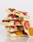 Stack of white chocolate bark with strawberries and nuts on a light background