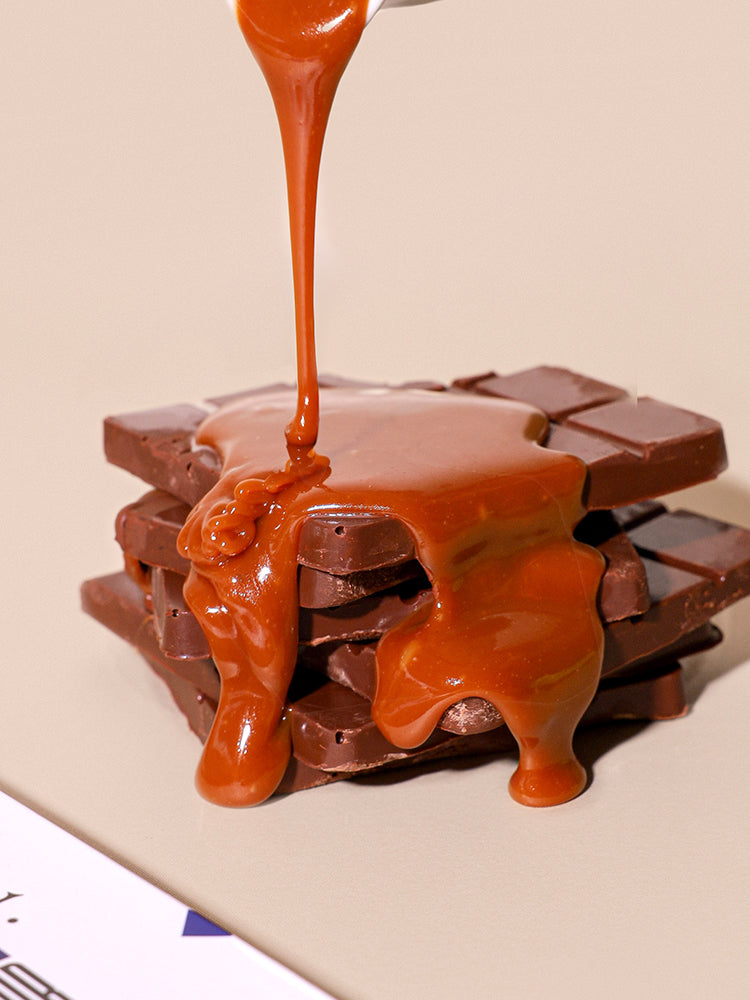 Caramel being poured over a chocolate bar on a beige background