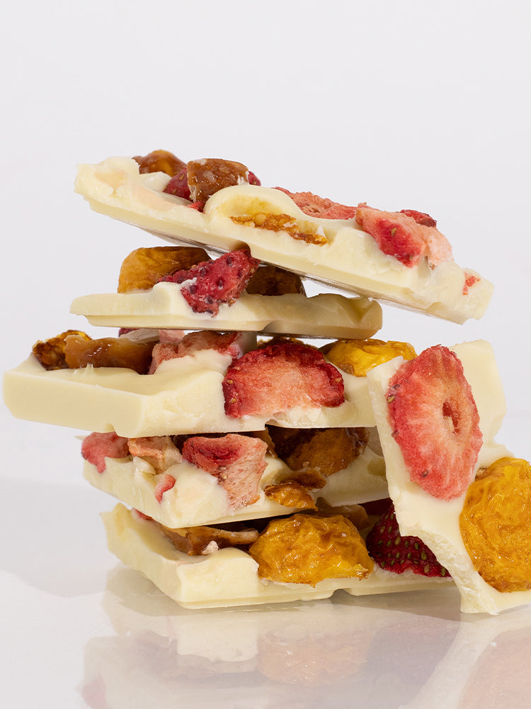 Stack of white chocolate bark with strawberries and nuts on a light background