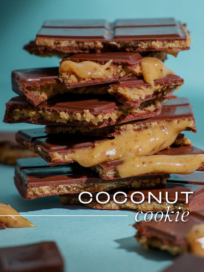 Stack of coconut cookie chocolate bars on a teal background with 'COCONUT cookie' text.